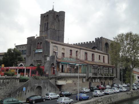 6.10.2009 Altra imatge des de l'Érol, on un cop més destaca la seva imponent torre-campanar de 35 m d'alçada del s. XIII, una torre ben be castellera. L'edifici annex —el qual presenta una façana clara— i que està edificat paral·lelament al riu, fou bastit en el s. XII amb funció residencial pels bisbes, funció que estigué en vigor fins el 1760. Ara forma part de les instal·lacions de l'hotel de la <em>Galiote</em>.                                                       -  Jordi Bibià