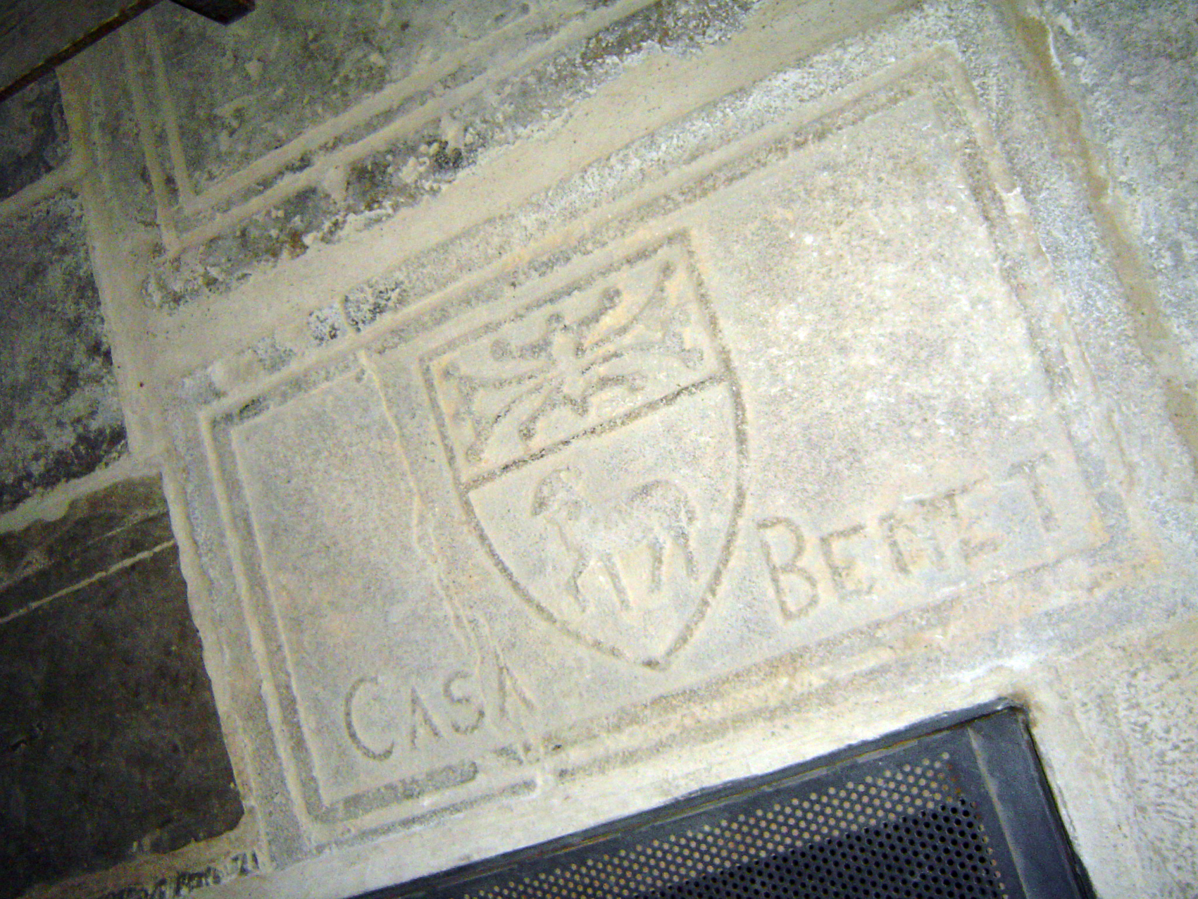 17.05.2009 Llosa sepulcral de la família Benet (d'origen occità). Veiem clarament la creu de Tolosa adaptada a la part superior de l'escut.Es troba ben aprop de l'escala d'accés a la baixada del refugi practicat en els sotaerranis del temple durant la Guerra Civil (a la dreta de la nau).           Santa Maria d'Agramunt -  Jordi Bibià